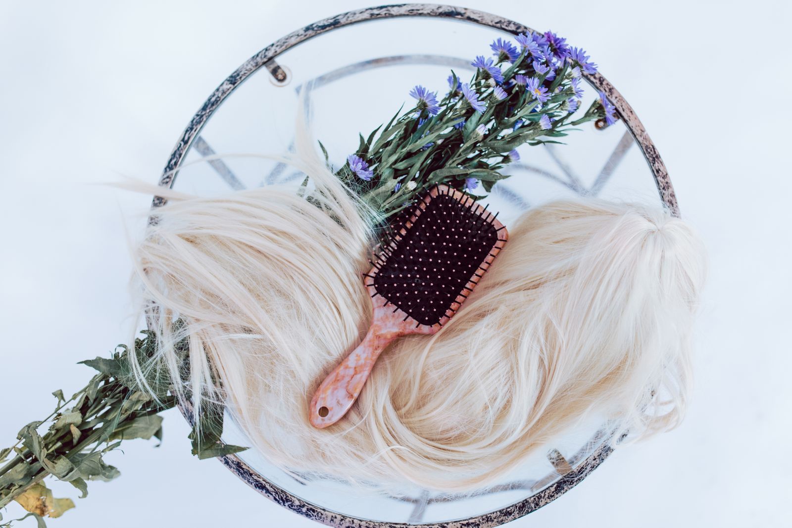 Perruque blonde et brosse à cheveux en composition sur fond sombre